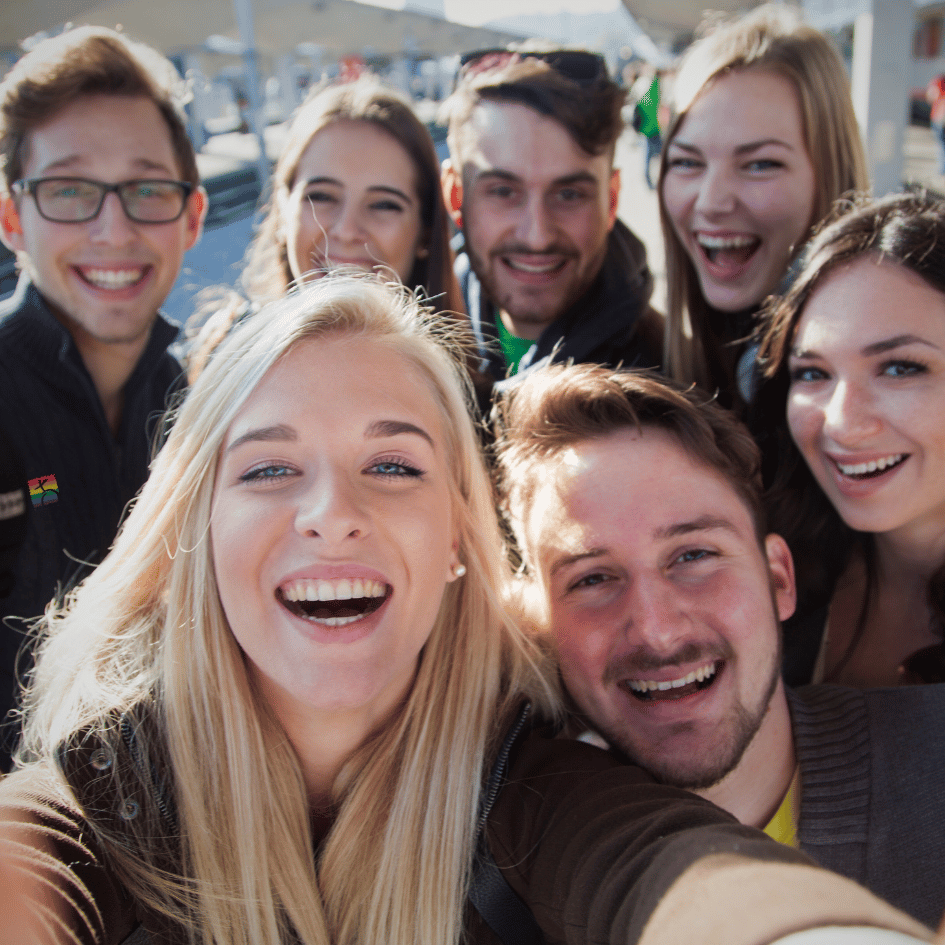Gruppe junger Menschen lacht gemeinsam in die Kamera – fröhliches Selfie bei Tageslicht