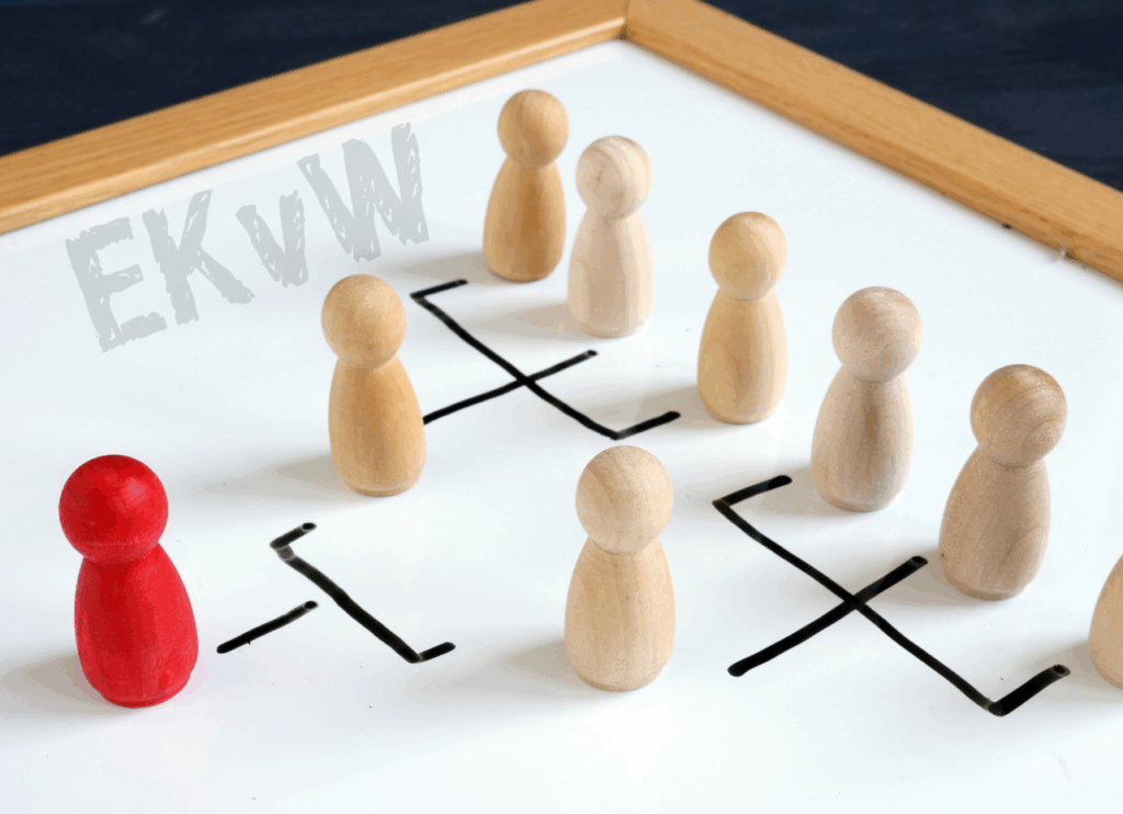 Holzfiguren auf Whiteboard mit Organigramm-Linien, vorne eine rote Figur; Schriftzug „EKvW“.