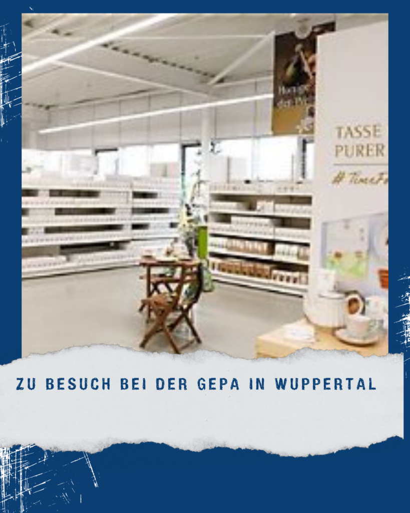 Einblick in die GEPA-Weltladen- und Ausstellungsfläche in Wuppertal mit Regalen, Fair-Trade-Produkten und dem Hinweis „Zu Besuch bei der GEPA in Wuppertal“